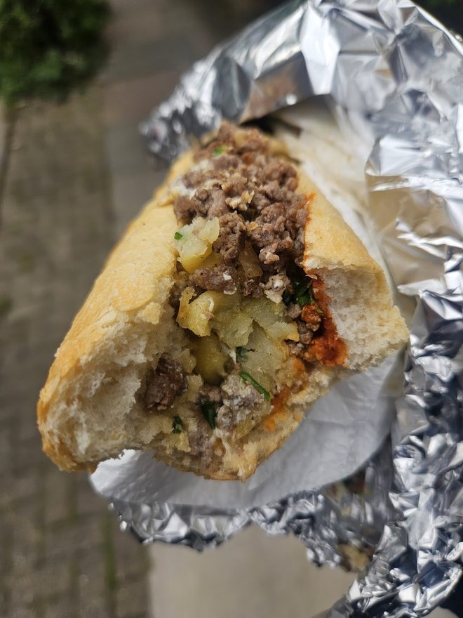A half-eaten sandwich held in its foil.
